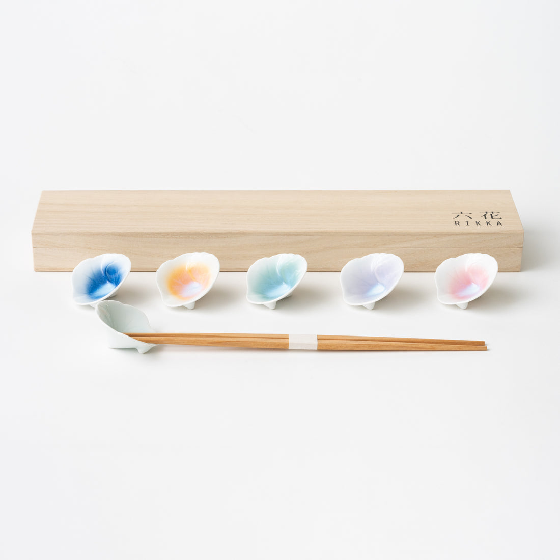 Ceramic chopstick rests in the shape of a flower. Colors in blue, orange, green, pink and lavender. Comes in a wooden box